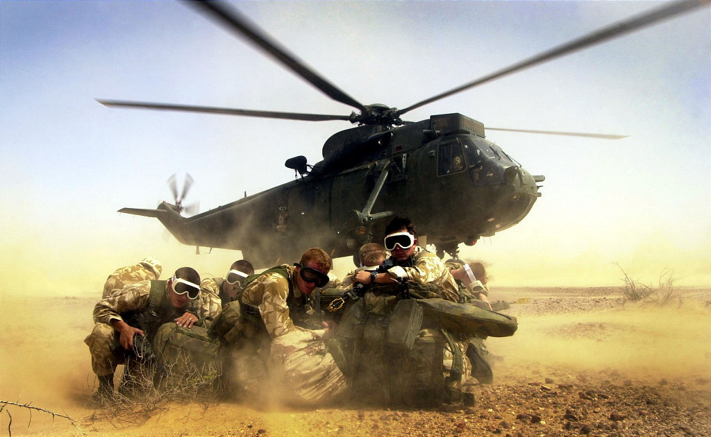 Royal Marines from 40 Commando go into a huddle as the Royal Navy Seaking h