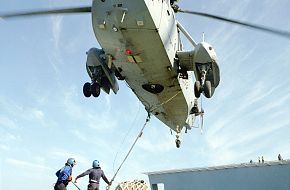 Sea King helicopter doing VERTREP (Vertical Replenishment at Sea).
